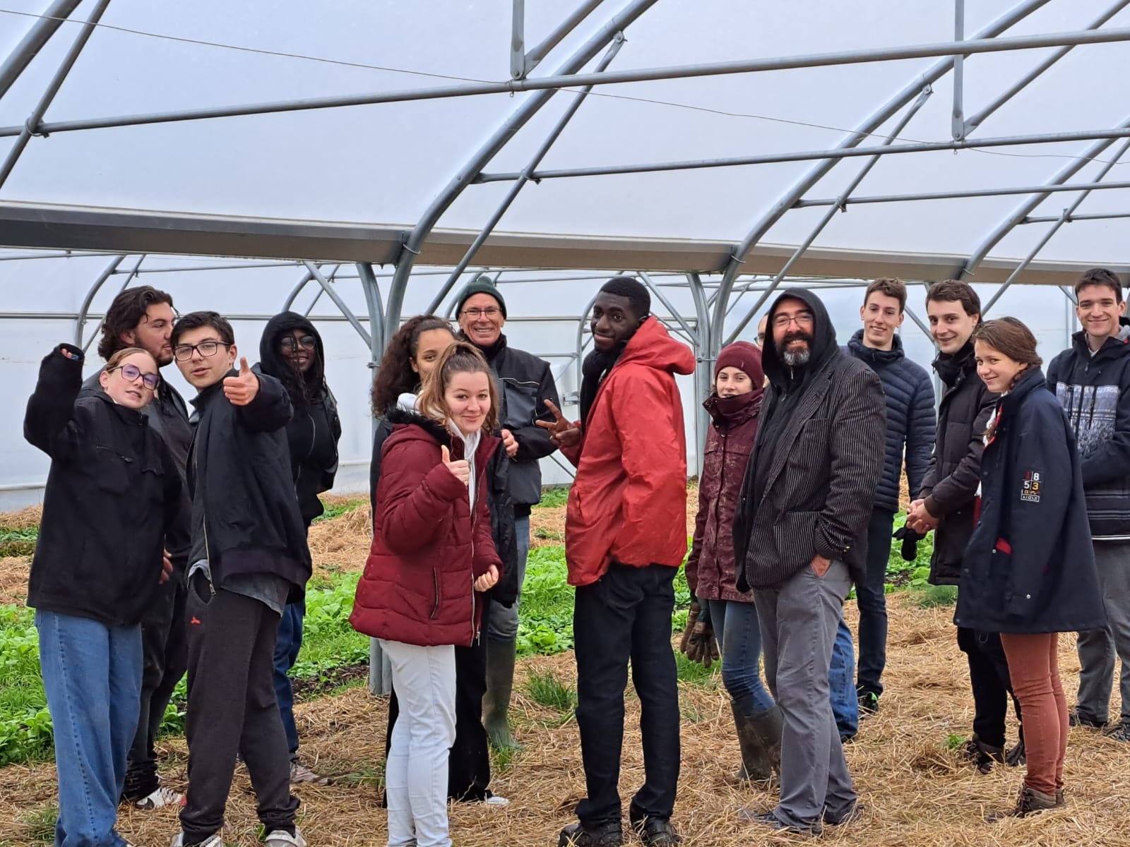 Groupe de jeunes en visite sous une serre à Grâce au Jardin